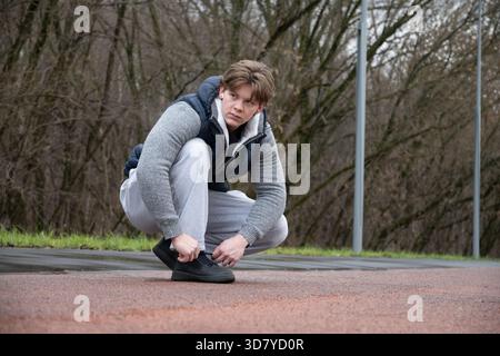 Hübscher junger sportlicher Mann, der Schnürsenkel vor dem Training und dem Training im Freien im öffentlichen Park schnürt. Im Freien. Stockfoto