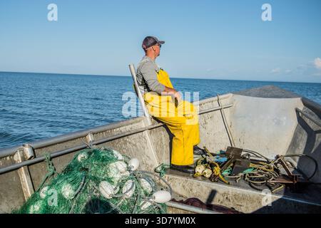 Ein kommerzieller Fischer in gelben Lätzchen auf dem Bug eines Bootes, Kalgin Island, Alaska. Stockfoto