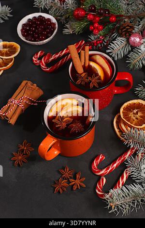 Starker alkoholischer oder alkoholfreier Cocktail in eisernen Bechern, Glühwein mit Gewürzen, Sternanis, Preiselbeeren, Orange, Apfel und Zimt, wärmender Winter Stockfoto