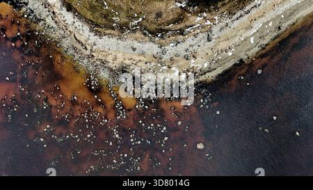 Abstrakte Luftaufnahme von oben nach unten auf die felsige Küste und das dunkle Wasser Stockfoto