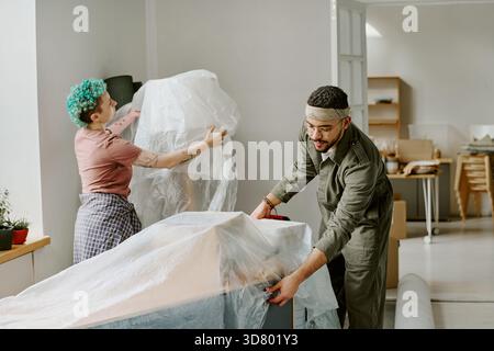 Junge Multiethnische Paare Packen Möbel Aus, Während Sie Neue Wohnung Renovieren Stockfoto