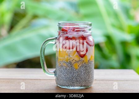 Mandelmilch chia Milchreis mit frischen Erdbeeren und Mango in einem Glas mug. Vegan raw Frühstück. Chia Samen und frisch geschnittenes Obst und Beeren desser Stockfoto