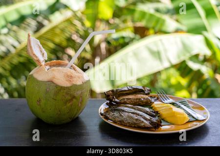 Im thailändischen Stil Dessert, gelbe Mango mit Banane klebriger Reis in der Palm Blätter und grüne Kokosnuss. Gelbe Mango und klebriger Reis ist beliebt traditionelle Dessert Stockfoto