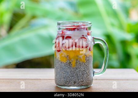 Mandelmilch chia Milchreis mit frischen Erdbeeren und Mango in einem Glas mug. Vegan raw Frühstück. Chia Samen und frisch geschnittenes Obst und Beeren desser Stockfoto