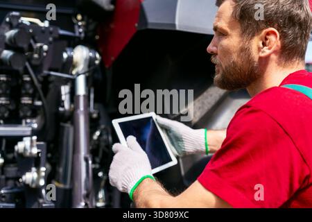 Landmaschinentechniker mit Tablet für die Gerätediagnose Stockfoto