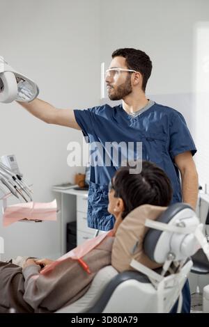 Männlicher Zahnarzt, der zahnärztliche Geräte für den Patienten vorbereitet Stockfoto