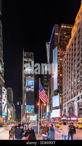 Farben und Lichter beleuchten den Times Square, während sich die Menschen bei Nacht in der lebhaften Atmosphäre von Manhattan versammeln und eine lebendige urbane Szene schaffen. Stockfoto