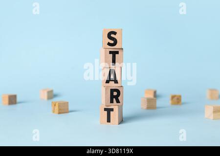 Holzwürfel mit WORTBEGINN auf blauem Hintergrund Stockfoto