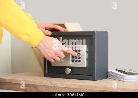 Mann öffnet den Safe zu Hause im Regal, Nahaufnahme Stockfoto