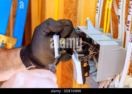 Facharbeiter installieren Leistungsschalter zu Hause und tragen Handschuhe mit Bohrwerkzeugen Stockfoto