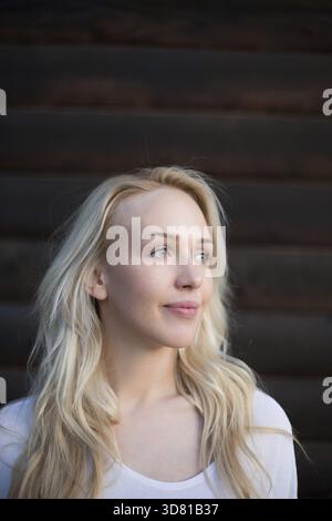 Modische Frau posiert draußen auf hölzernem Hintergrund Stockfoto
