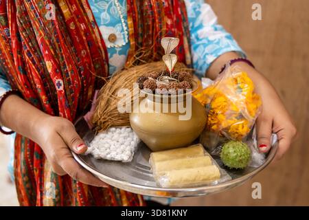 Frau mit traditionellem pooja-Thali mit Blumen, Kokosnuss und heiligen Gegenständen im Tempel Stockfoto