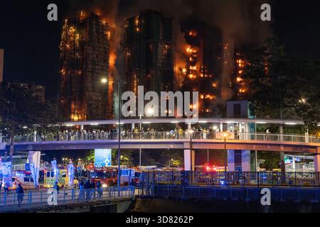Am 26. November 2025 brach Ein Feuer im Wohnkomplex Wang Fuk Court im Tai Po District, New Territories, Hongkong aus. Viele Menschen standen auf der Brücke und beobachteten das Feuer des Hong Kong Tower. Der Brand wurde als Brand mit fünf Alarmen eingestuft, die örtlichen Behörden haben mindestens 83 Tote (einschließlich eines Feuerwehrmannes), 77 Verletzte und Hunderte von Vermissten gemeldet. Die Brandursache wird noch untersucht. Dieses Foto wurde an der Tai Po Road aufgenommen. Es war taffische Marmelade wegen des Unfalls. (Foto: Cheng Wai Hok/SIPA USA) Stockfoto