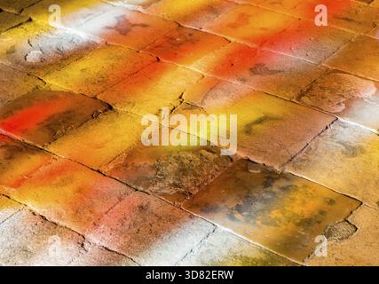 Bunte Lichter auf dem Boden, die durch ein rot-gelbes Fenster die Sonne strahlen lassen Stockfoto