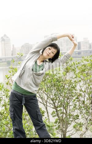 Reife Frau Asiens dehnt ihren Körper im Outdoor Park Stockfoto