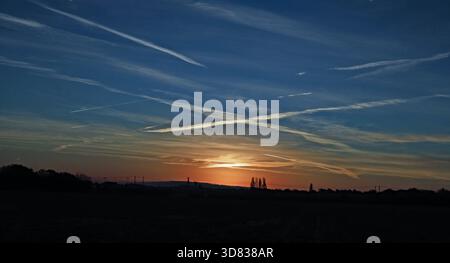 CW 9326 Kreuz am Himmel 26.11.2025. Wenn die Sonne östlich von Burscough in West Lancashire aufgeht, beleuchtet sie die Dampfspuren des Flugzeugs über dem t Stockfoto