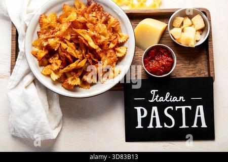 Hausgemachte, Trendige Pasta Chips. Knusprig scharfe Pasta Farfalle mit Parmesan in einer Schüssel auf hellem Hintergrund. Draufsicht. Stockfoto