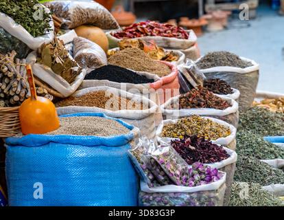 Ein farbenfroher Marktstand voller verschiedener Kräuter, lebhafter Tees (Rosenknospen, Kamille) und Gewürzen in gewebten Säcken, darunter ein markanter orangener sco Stockfoto
