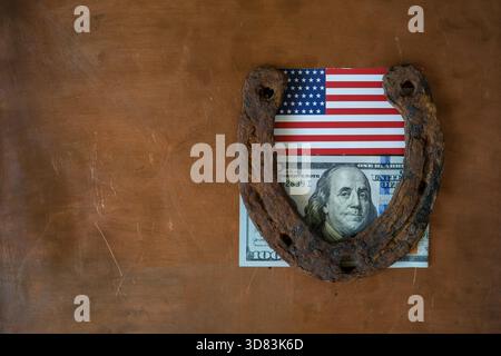 Rusty Hufeisen, ein 100-Dollar-Schein und eine amerikanische Flagge auf einem Kupfer-Metall-Hintergrund. Glücksland. Hufeisenfahne. Symbol für Glück. Draufsicht. Stockfoto
