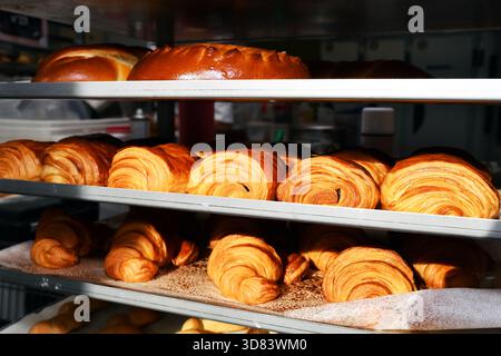 ein Backregal gefüllt mit frisch gebackenen französischen Viennese, darunter goldene Croissants und laminierte Gebäck wie Pains au Chocolat - Frankreich Stockfoto