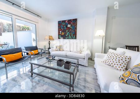 Modernes Wohnzimmer mit weißem Sofa und Glastisch Stockfoto