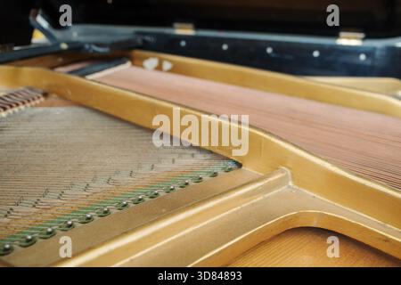 Eine Makroaufnahme der kupferumwickelten Basssaiten in einem offenen Flügel. Die geringe Tiefe des Feldes konzentriert sich auf die Textur des Metallwindes Stockfoto