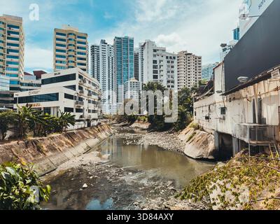 Städtischer Kanal, der durch Panama City verläuft, umgeben von hohen modernen Gebäuden, die natürliche Wasserstraße mit dichter Stadtentwicklung kontrastieren Stockfoto