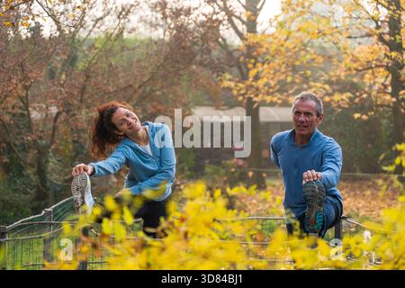 Paare, die morgens Dehnübungen in einem wunderschönen Herbstpark machen, der sich auf Wellness konzentriert Stockfoto