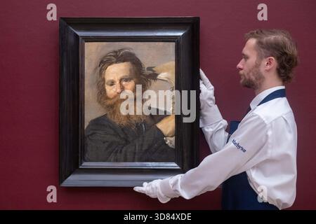 London, England, Großbritannien. November 2025. Ein Kunstschaffender hält Frans Hals’ Portrait of Verdonck Brandishing a Jawbone, geschätzt auf 800.000-1.200.000 GBP, während einer Vorschau in Sothebys in London am 28. November 2025. Das Gemälde wird am 3. Dezember im Verkauf von Gemälden der Alten Meister und des 19. Jahrhunderts angeboten. (Kreditbild: © Thomas Krych/ZUMA Press Wire) NUR REDAKTIONELLE VERWENDUNG! Nicht für kommerzielle ZWECKE! Stockfoto