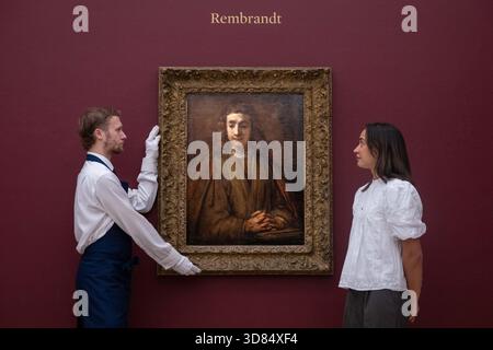 London, England, Großbritannien. November 2025. Sothebys-Mitarbeiter stehen neben Rembrandt Harmensz. Van Rijn's Saint John on Patmos, geschätzt auf 5.000.000 bis 7.000.000 GBP, während einer Vorschau in Sothebys in London am 28. November 2025. Das Gemälde wird am 3. Dezember im Verkauf von Gemälden der Alten Meister und des 19. Jahrhunderts angeboten. (Kreditbild: © Thomas Krych/ZUMA Press Wire) NUR REDAKTIONELLE VERWENDUNG! Nicht für kommerzielle ZWECKE! Stockfoto