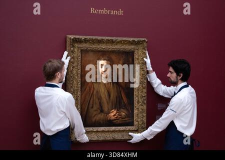 London, England, Großbritannien. November 2025. Sothebys-Mitarbeiter stehen neben Rembrandt Harmensz. Van Rijn's Saint John on Patmos, geschätzt auf 5.000.000 bis 7.000.000 GBP, während einer Vorschau in Sothebys in London am 28. November 2025. Das Gemälde wird am 3. Dezember im Verkauf von Gemälden der Alten Meister und des 19. Jahrhunderts angeboten. (Kreditbild: © Thomas Krych/ZUMA Press Wire) NUR REDAKTIONELLE VERWENDUNG! Nicht für kommerzielle ZWECKE! Stockfoto