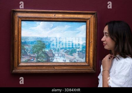 London, England, Großbritannien. November 2025. Ein Mitarbeiter von Sothebys steht neben Hans Bols Panoramalandschaft mit einem Turm und einem Fluss im Vordergrund und einem Blick auf Antwerpen und den Fluss Schelde in der Ferne, geschätzt auf 600.000-800.000 GBP, während einer Vorschau in Sothebys in London am 28. November 2025. Das Gemälde wird am 3. Dezember im Verkauf von Gemälden der Alten Meister und des 19. Jahrhunderts angeboten und ist derzeit neben außergewöhnlichen Werken von Rubens, Durer, Brueghel dem Jüngeren, Frans Hals, Rembrandt, und andere im Rahmen der öffentlichen Ausstellungen der Old Masters Week. (Guthaben Im Stockfoto