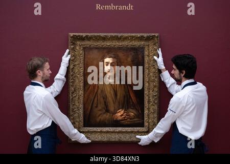 London, England, Großbritannien. November 2025. Sothebys-Mitarbeiter stehen neben Rembrandt Harmensz. Van Rijn's Saint John on Patmos, geschätzt auf 5.000.000 bis 7.000.000 GBP, während einer Vorschau in Sothebys in London am 28. November 2025. Das Gemälde wird am 3. Dezember im Verkauf von Gemälden der Alten Meister und des 19. Jahrhunderts angeboten. (Kreditbild: © Thomas Krych/ZUMA Press Wire) NUR REDAKTIONELLE VERWENDUNG! Nicht für kommerzielle ZWECKE! Stockfoto