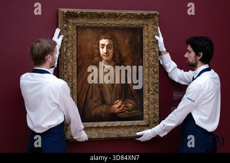 London, England, Großbritannien. November 2025. Sothebys-Mitarbeiter stehen neben Rembrandt Harmensz. Van Rijn's Saint John on Patmos, geschätzt auf 5.000.000 bis 7.000.000 GBP, während einer Vorschau in Sothebys in London am 28. November 2025. Das Gemälde wird am 3. Dezember im Verkauf von Gemälden der Alten Meister und des 19. Jahrhunderts angeboten. (Kreditbild: © Thomas Krych/ZUMA Press Wire) NUR REDAKTIONELLE VERWENDUNG! Nicht für kommerzielle ZWECKE! Stockfoto