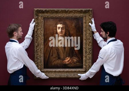 London, England, Großbritannien. November 2025. Sothebys-Mitarbeiter stehen neben Rembrandt Harmensz. Van Rijn's Saint John on Patmos, geschätzt auf 5.000.000 bis 7.000.000 GBP, während einer Vorschau in Sothebys in London am 28. November 2025. Das Gemälde wird am 3. Dezember im Verkauf von Gemälden der Alten Meister und des 19. Jahrhunderts angeboten. (Kreditbild: © Thomas Krych/ZUMA Press Wire) NUR REDAKTIONELLE VERWENDUNG! Nicht für kommerzielle ZWECKE! Stockfoto