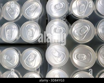 Draufsicht auf Aluminium-Getränkedosen, die fest in Schrumpffolie verpackt sind. Sich wiederholende Muster von Dosenoberflächen, Getränkeindustrie, Massenproduktion und Recycling. Stockfoto