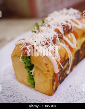 Frisch gegrilltes, leckeres Sandwich mit Belag und Füllung auf weißem Teller, frisch gebacken im Restaurant Stockfoto