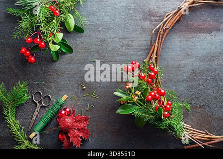 Weihnachtskränze aus natürlichen Zweigen von Fichte, wacholder und stechpalmen-roten Beeren. Dekorationen für den weihnachtskranz zu Hause Stockfoto