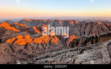 Sonnenlicht über den roten Bergen des Mount Sinai und die stille Schönheit der Wüstengipfel während des Aufstiegs zum Berg Moses Stockfoto