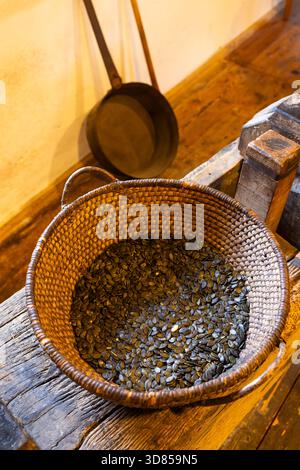 Korb gefüllt mit Steirischer Kurbiskerne auf Holzfläche in Heimschuh, Österreich Stockfoto