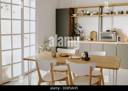 Leere, moderne Küche mit Holztisch und Frühstückseinrichtung Stockfoto