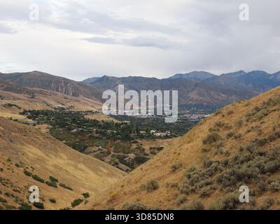 Hochwinkelblick mit Blick in ein trockenes, zerklüftetes Bergtal mit Vorstadtentwicklung im fernen Zentrum. Stockfoto