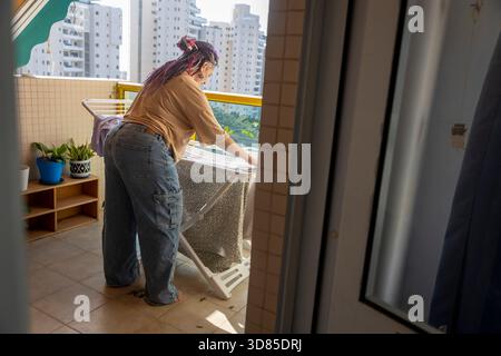 Reife Frau mit Dreadlocks und kurvigen Körperbekleidung auf dem Wäscheständer auf dem Balkon des Apartments Stockfoto
