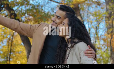 Lächelndes hispanisches Paar lächelndes Gespräch über Date im Herbst Park Talk auf Blattgold Herbstsaison in der Stadt Glückliche Frau mit Mann umarmt Stockfoto