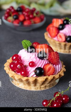 Hausgemachte Shortbread Körbe mit Creme und frischen Beeren auf grauem Hintergrund Stockfoto
