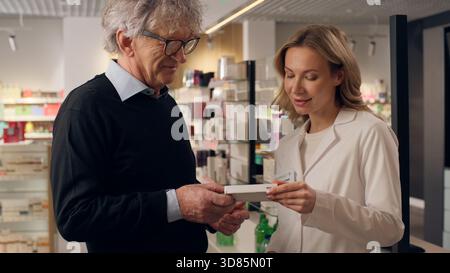 Alter Senior Mann Kunde kaufen Herztabletten in der Apotheke medizinische Hilfe Frau Arzt Pflegekraft Apotheker konsultieren Patienten Medizin Vitamine Drogen Herz Stockfoto