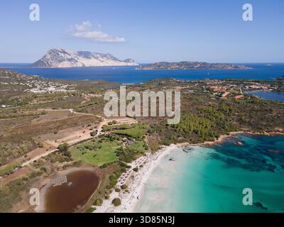 Aus der Vogelperspektive auf das türkisfarbene Meer, das sanft den unberührten weißen Sand von Cala Brandinchi küsst, umgeben von üppiger grüner Vegetation, San Teodoro, Sardinien, I Stockfoto