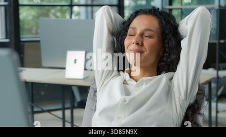 Entspannte glückliche hispanische Geschäftsfrau im Büro Hände hinter Kopf Ruhepause lächelnde positive Geschäftsfrau entspannen träumen Denken Stockfoto