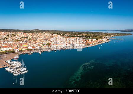 Eine lebhafte Küstenstadt erstreckt sich entlang der Küste mit farbenfrohen Häusern und einem lebhaften Yachthafen, Sardinien, Italien Stockfoto