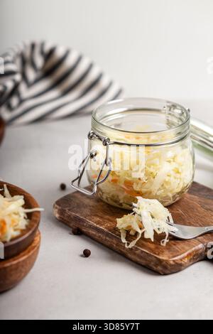 Sauerkraut mit Karotten in einem Glas auf grauem Hintergrund. Ein Snack voller Vitamin C. Stockfoto